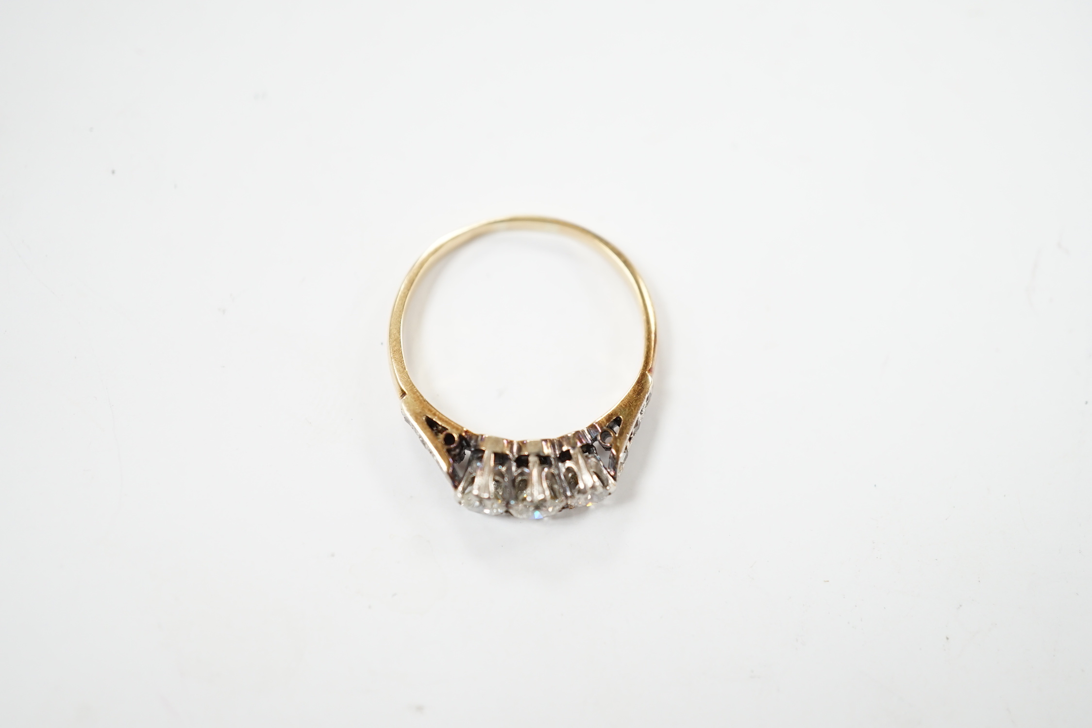 A yellow metal and three stone diamond set ring, with six stone diamond chip set shoulders, size L, gross weight 2.2 grams.